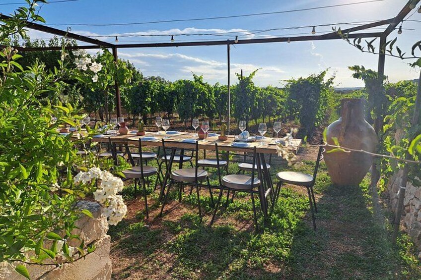 An outdoor dining area with tables and chairs, surrounded by greenery and a large vase. 2