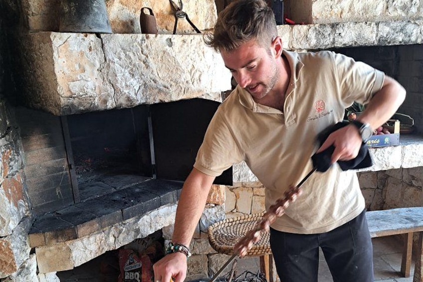 A person using a long-handled tool to manage a fire in a stone fireplace. 5