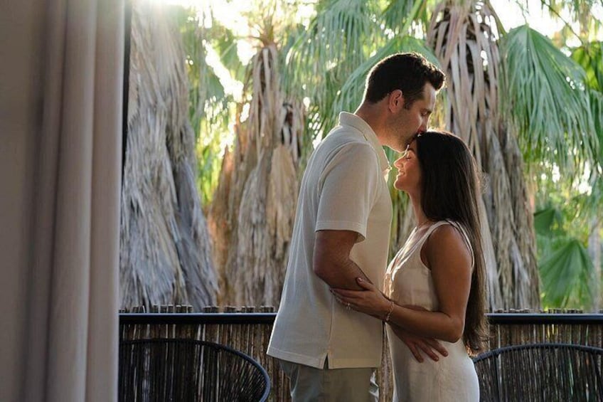 A couple embracing in a tropical setting with palm trees and a fence. 5