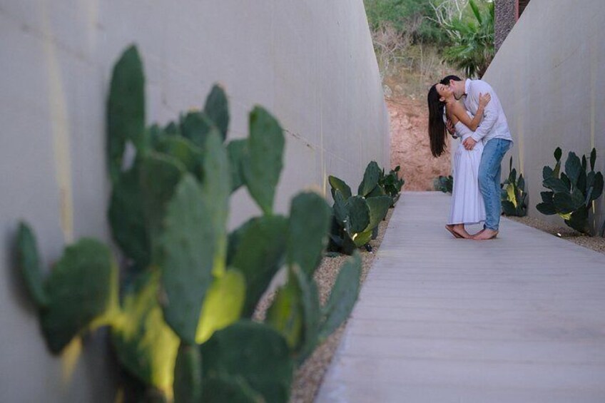 A couple embracing in a narrow pathway surrounded by cacti. 2