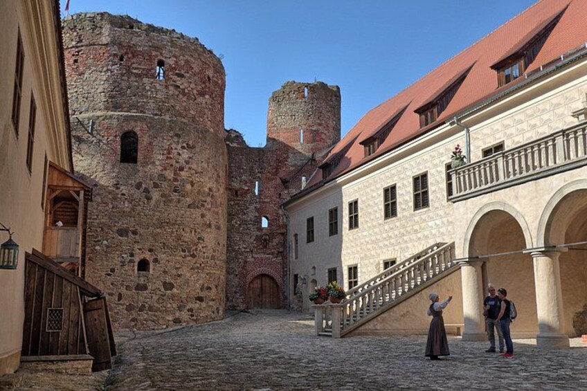 A cobblestone street, a stone tower, and a building with a balcony. 4