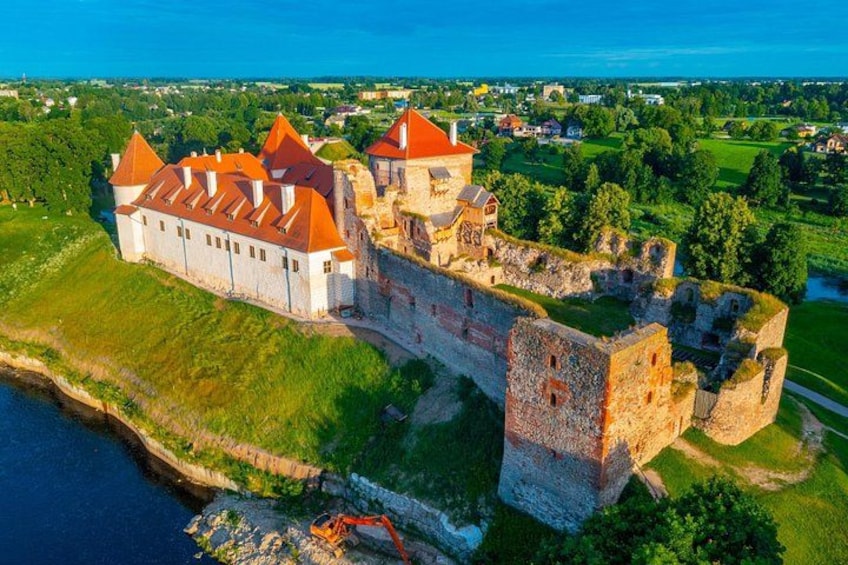 A castle with red roofs, a moat, and surrounding greenery. 5