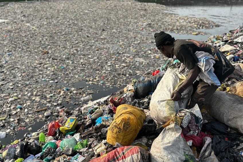 Eine Person durchwühlt Müll an einem verschmutzten Strand. 5