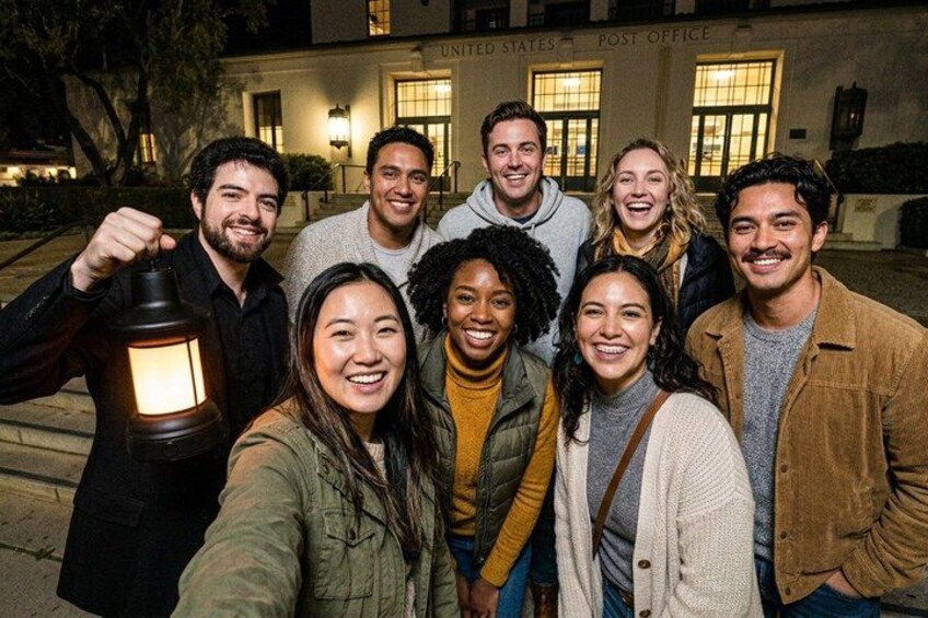 A group of people standing in front of a building with illuminated windows and a sign that reads 'United States Post Office.' 3