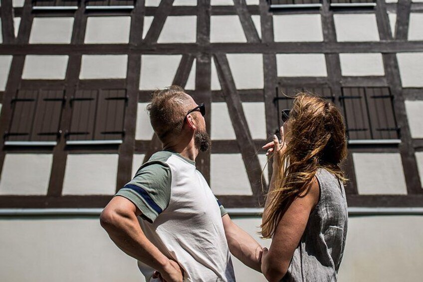 Een man en een vrouw staan voor een vakwerkhuis. 1
