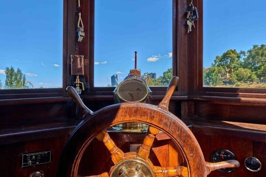 A wooden ship's wheel with a compass, a clock, and a window with a view of trees and buildings. 5