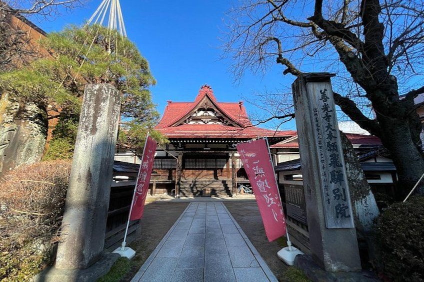 Une porte traditionnelle japonaise, avec un toit rouge, des piliers en pierre et des banderoles. 5