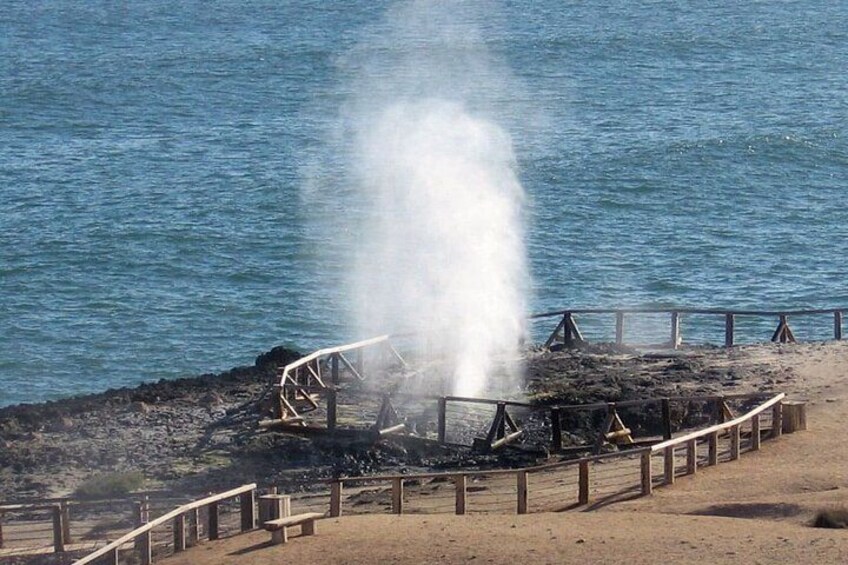 A damaged structure by the water with smoke or steam rising. 1