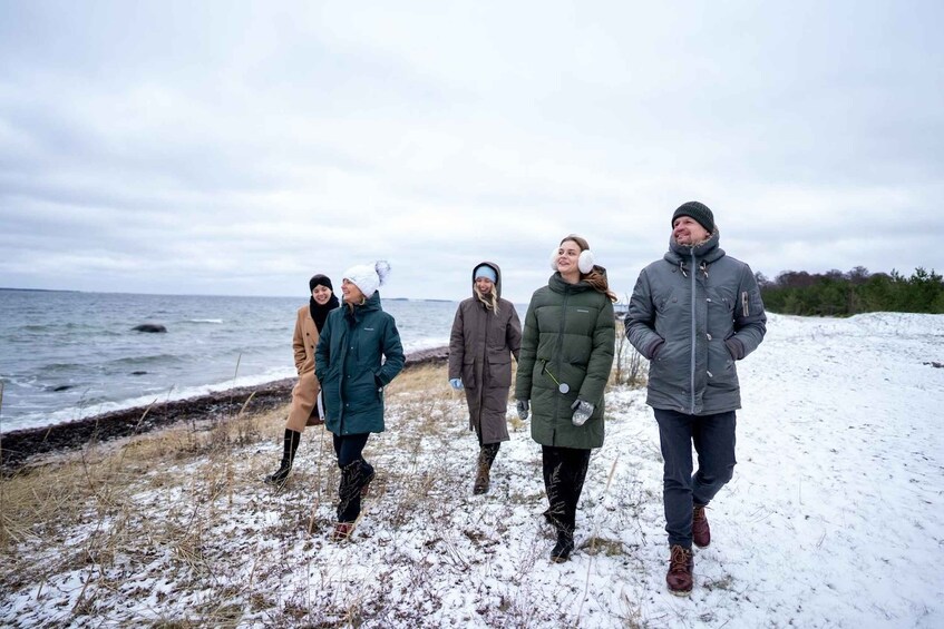 A group of people walking along a snowy shore with the sea in the background. 5