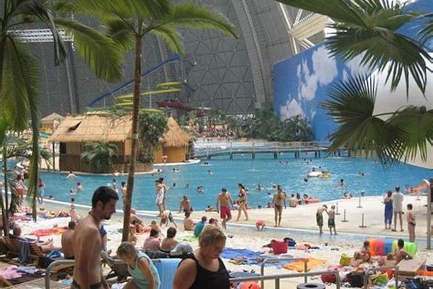 An indoor swimming pool with people swimming and sunbathing. 2