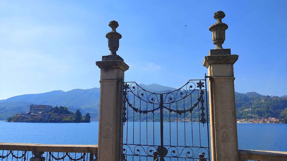 A wrought iron gate with ornate designs, overlooking a body of water with mountains in the background. 5