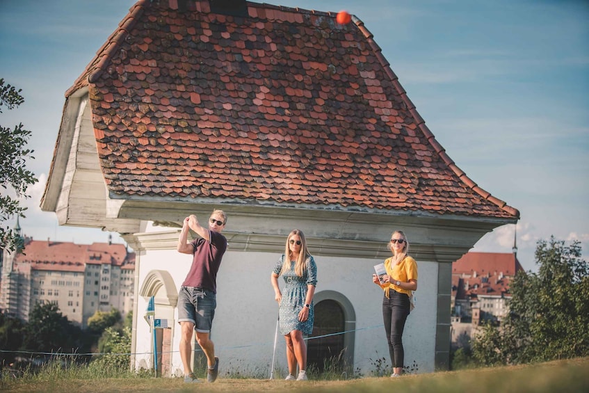Three people standing in front of a building with a red-tiled roof. 3