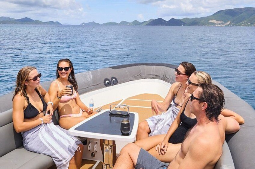 A group of people on a boat with a table and drinks. 5