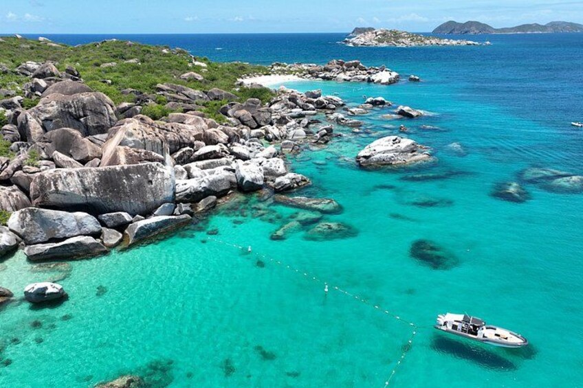 A turquoise sea with a boat, rocky coastline, and distant islands. 2