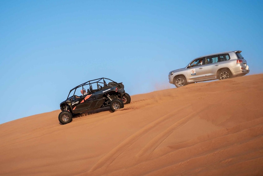 A black off-road vehicle and a silver SUV on a sandy dune. 2