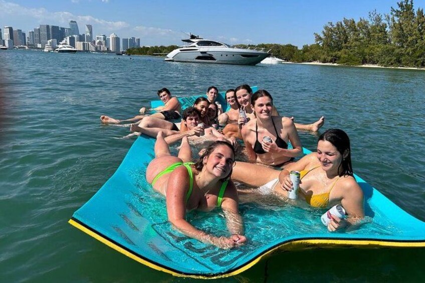 Un grupo de personas en un bote inflable azul en un cuerpo de agua, con un horizonte urbano de fondo. 2