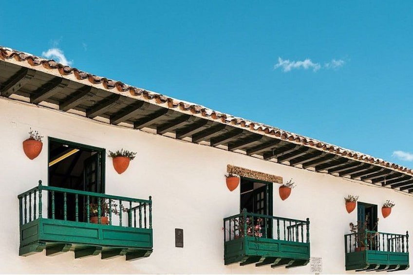 A building with a white facade, green balconies, and terracotta roof tiles. 4