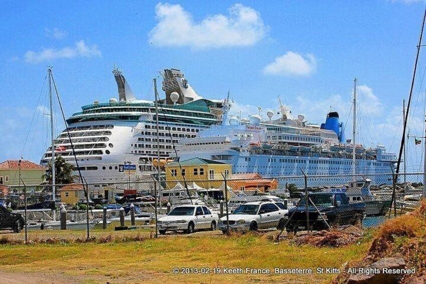 Un grand navire de croisière était amarré dans un port, avec de plus petits bateaux et des voitures au premier plan. 4