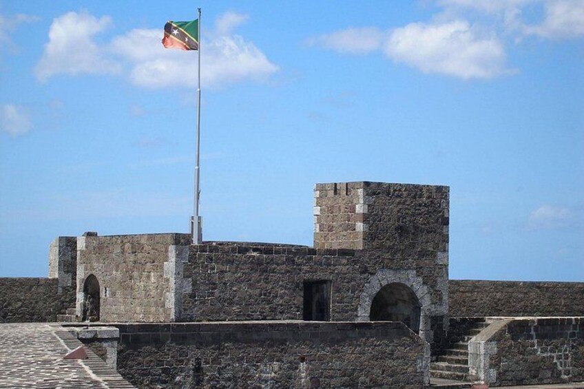 Une fortification en pierre, surmontée d’un mât pour drapeau, dotée de portails en arc de cercle et s’ouvrant sur un ciel dégagé. 5