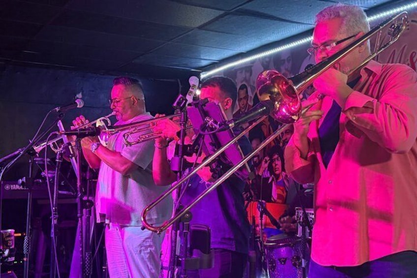 A brass band performing on stage with musicians playing trombones and a trumpet. 5