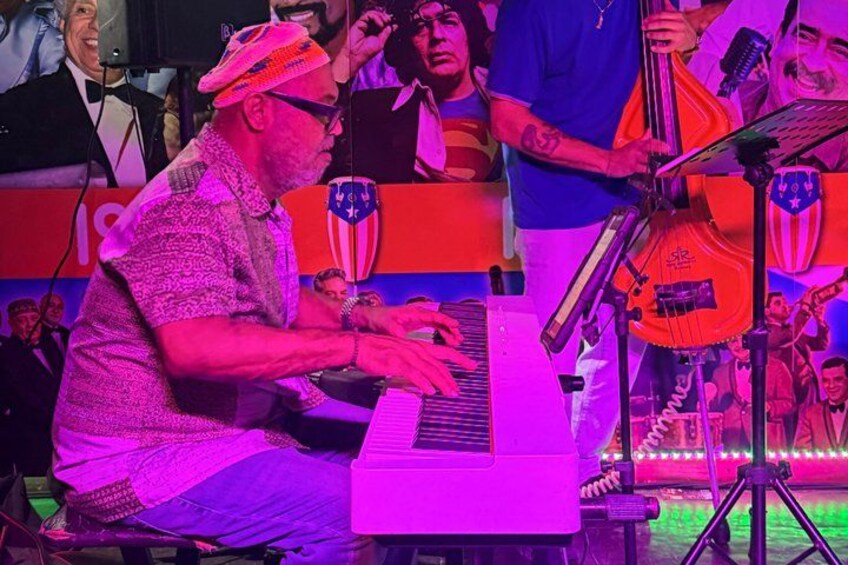A person playing a keyboard instrument on stage with a microphone stand in front. 3