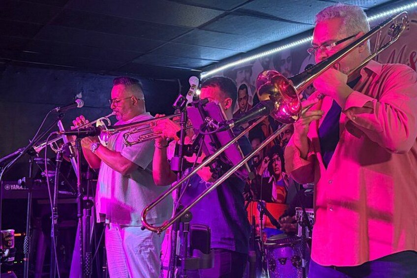 Blåsorkester optræder på scenen med musikere der spiller trombone og trompet. 3