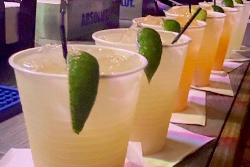 A row of plastic cups with lime wedges, possibly containing a beverage, on a tray. 4