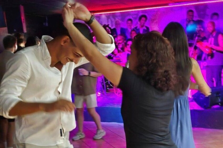 People dancing in a dimly lit room with purple lighting. 1