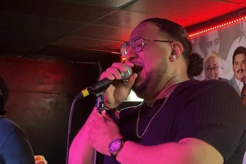 A person holding a microphone, wearing a purple shirt and a watch. 2