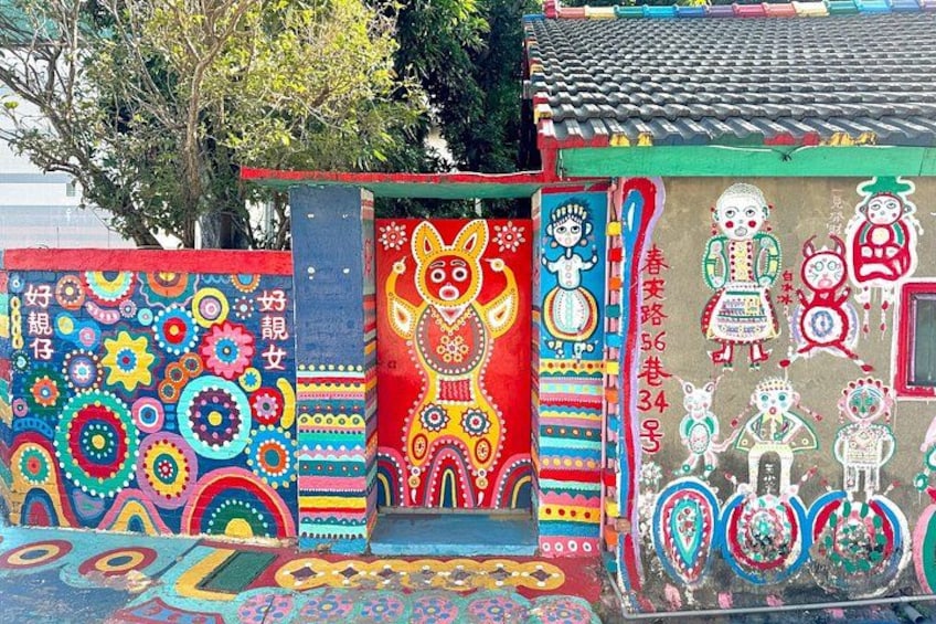 Une fresque colorée, ornée de divers motifs et dessins, dont une porte rouge bien visible sur laquelle est représentée une illustration de chat. 4