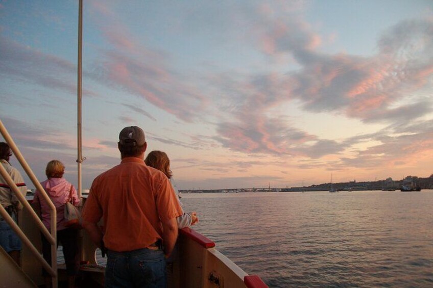 A sunset over a body of water with a boat and people on it. 3