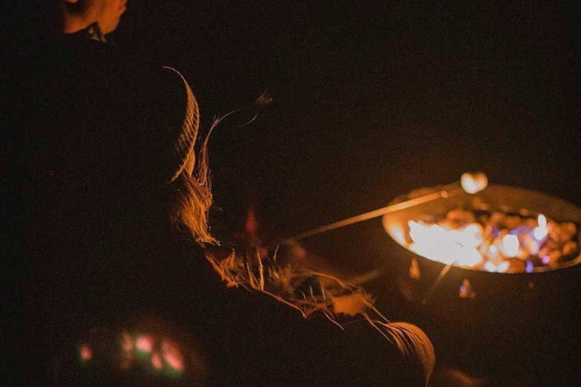 A person holding a stick with a fire in a pan. 3