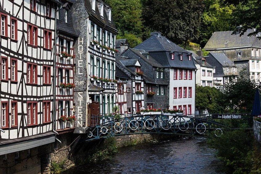 A traditional European town with half-timbered houses, a bridge over a river, and a sign for Hotel Stern. 5