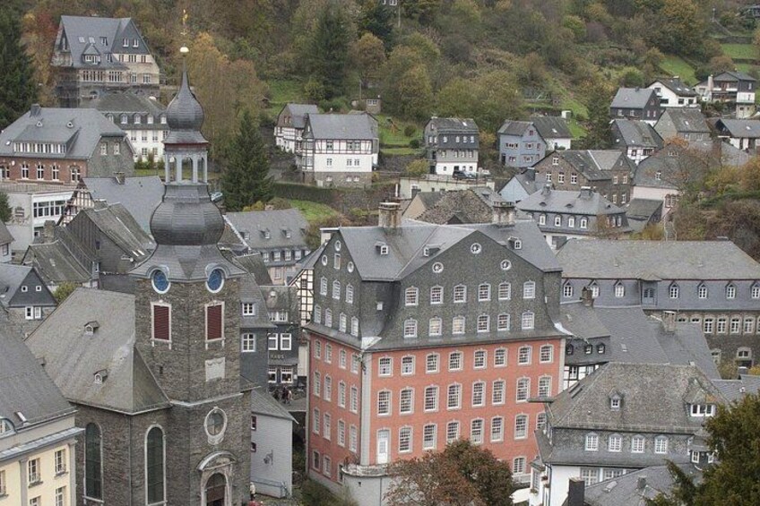 A town with historic buildings, including a prominent red building with a corner tower and a church with a dome. 4