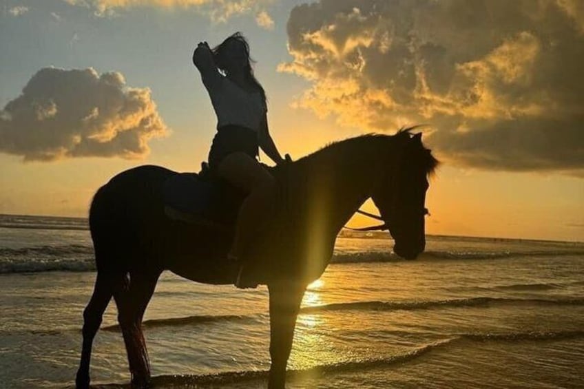 Una persona monta a caballo en la playa al atardecer. 2