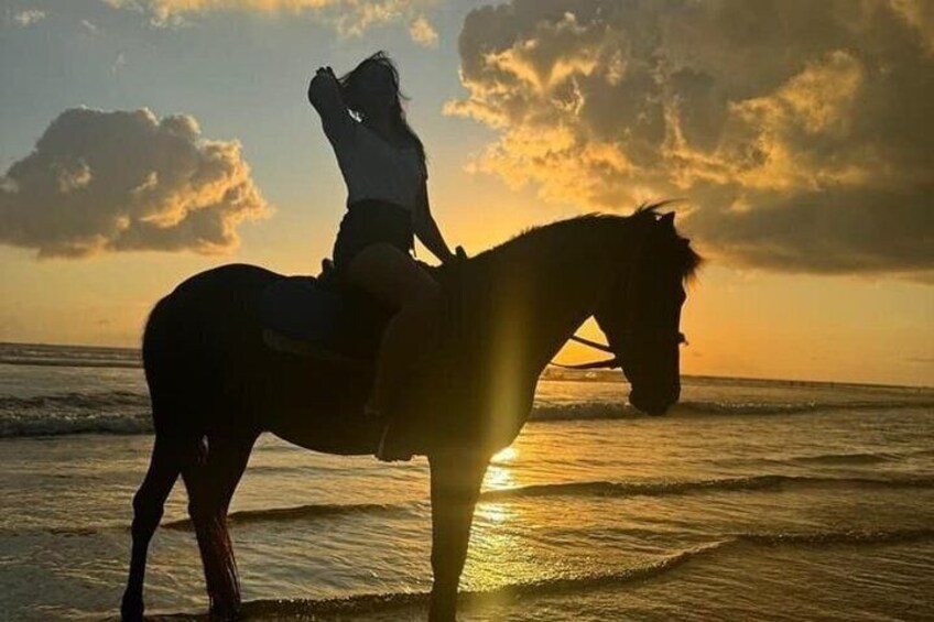 Una persona montando a caballo en una playa al atardecer. 2