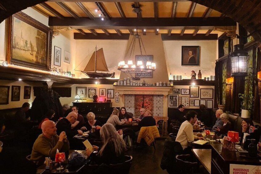 Un pub acogedor con clientes sentados en mesas, una chimenea y diversas decoraciones. 1