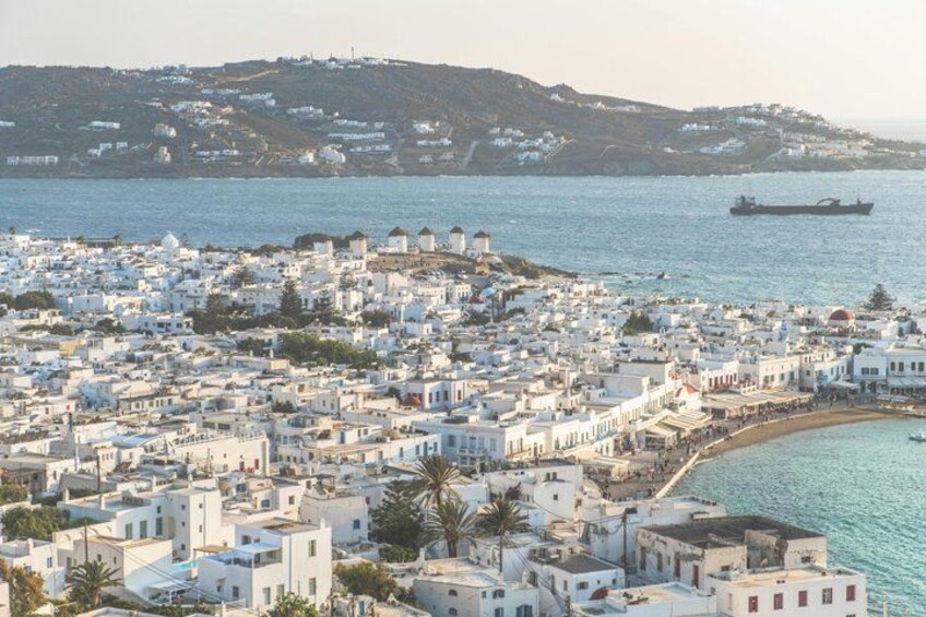 Un pueblo costero con edificios blancos, una playa y un barco grande a lo lejos. 5