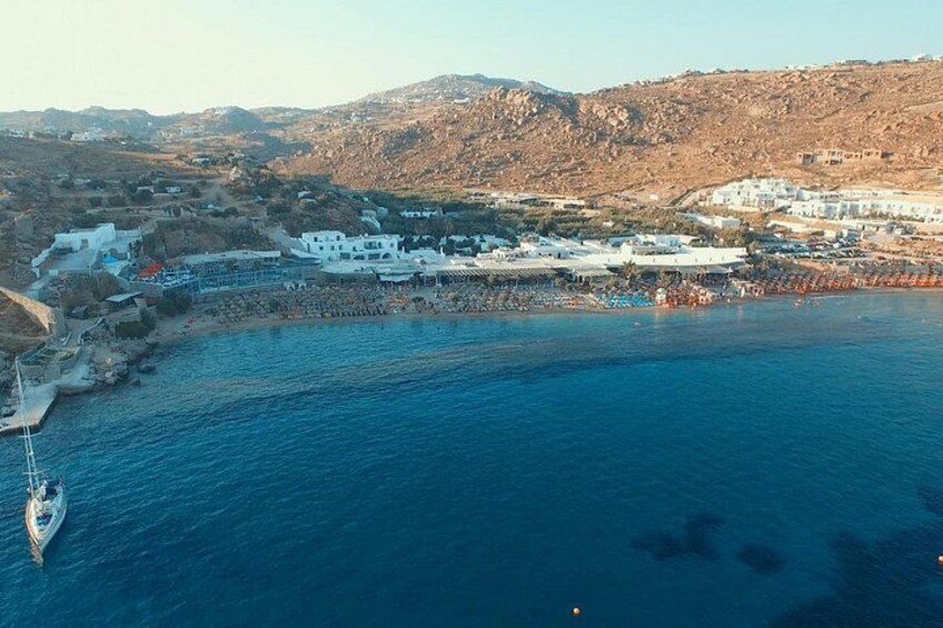 A coastal town with white buildings, a marina, and a hilly landscape in the background. 3