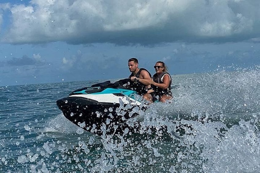 Two people on a jet ski in the ocean with splashing water. 1