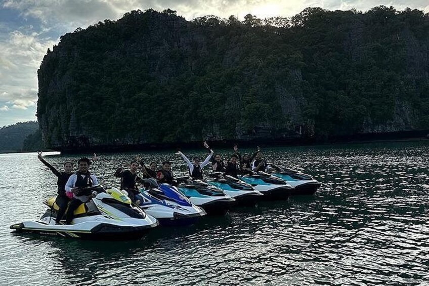 A group of people on jet skis in a body of water with a large, forested island in the background. 5