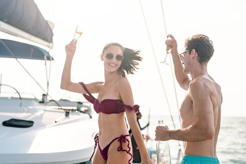 Two people on a sailboat, holding drinks. 1