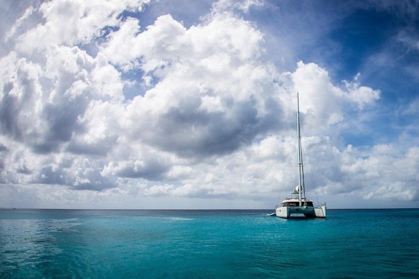A sailboat on turquoise water under a cloudy sky. 4