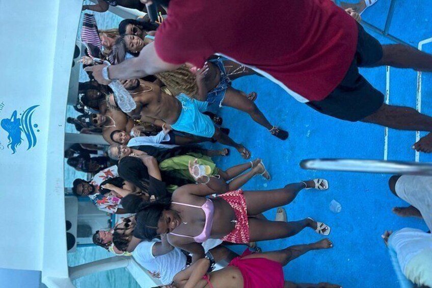 A group of people on a boat with a blue floor, some wearing swimwear. 2