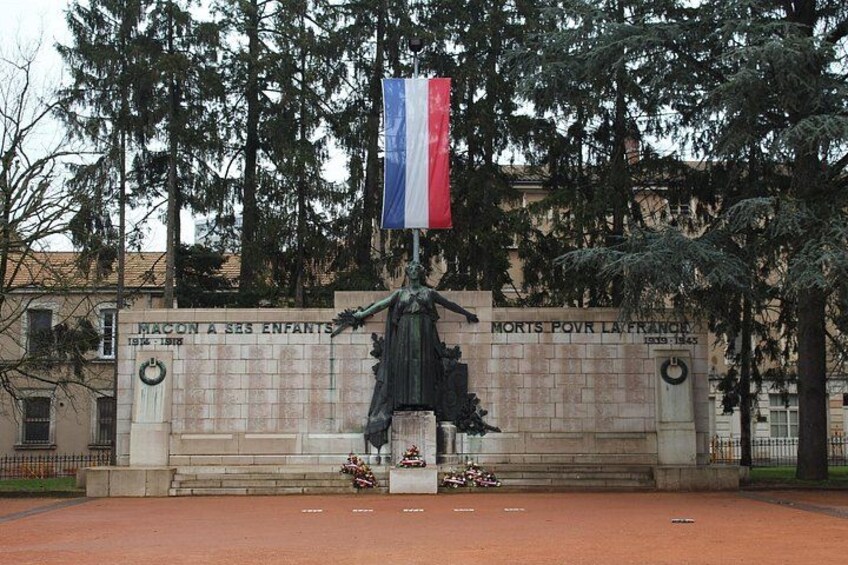 A monument with inscriptions, a flag, and a statue. 3