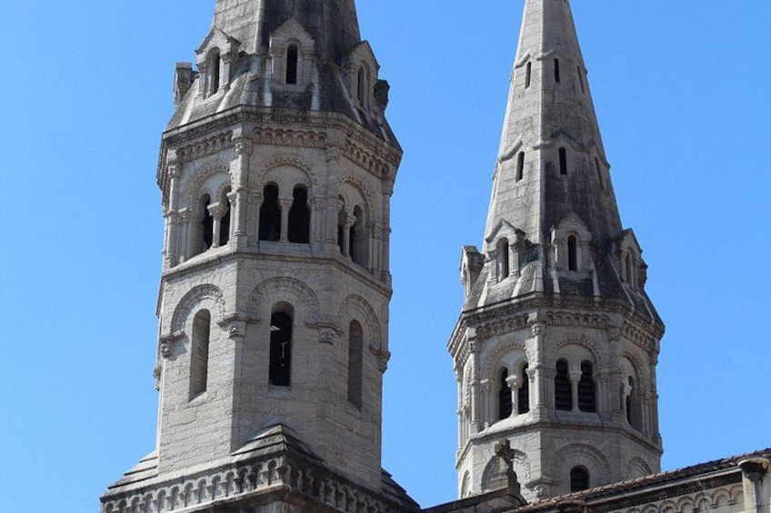 Two tall, historic towers with intricate architectural details against a clear blue sky. 1