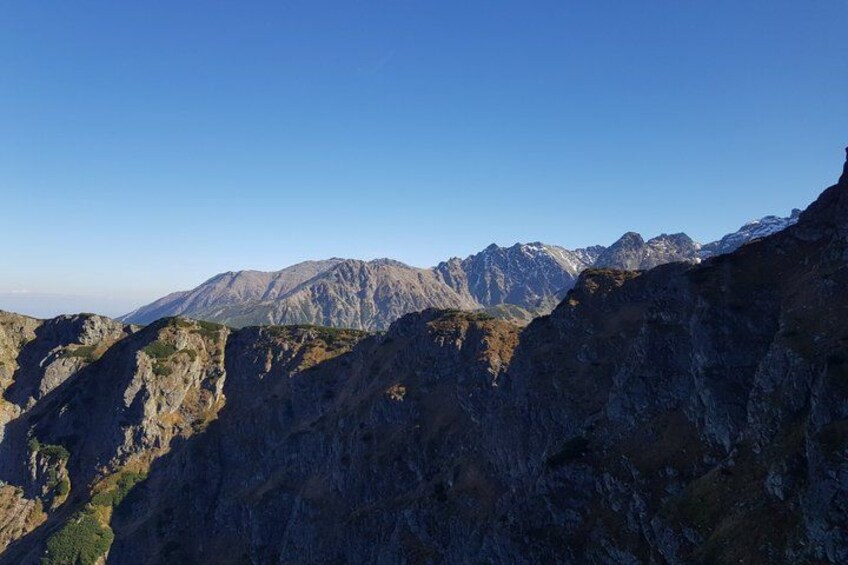 A mountainous landscape with rugged terrain and distant peaks under a clear sky. 2