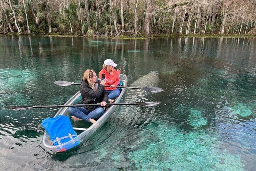 Two people in a small boat on a clear water body surrounded by trees. 4