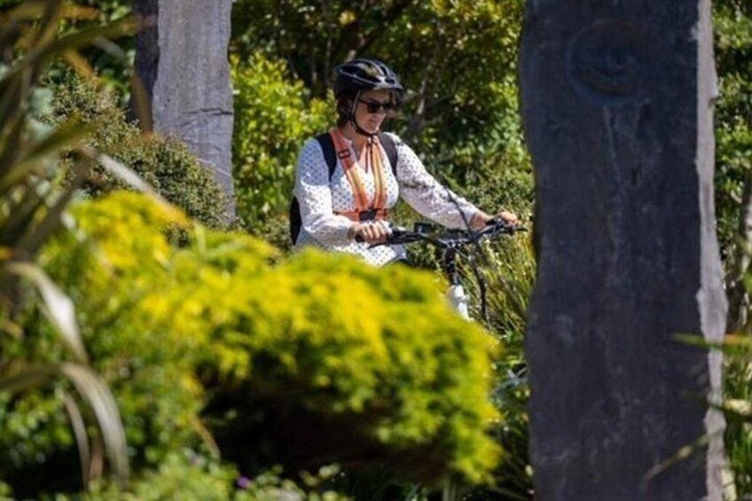 Eine Person fährt mit dem Fahrrad durch eine üppige, grüne Landschaft mit Bäumen und Büschen. 3