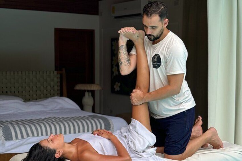 Een persoon ligt op een bed en krijgt een beenmassage van iemand anders. 1